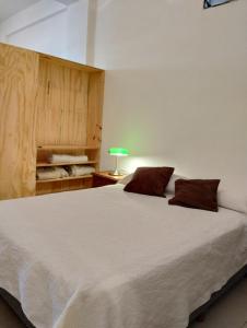 a bedroom with a large white bed with a green lamp at Hospedajes JUJUY in Palpalá