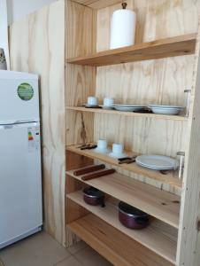 a kitchen with wooden shelves with dishes and a refrigerator at Hospedajes JUJUY in Palpalá