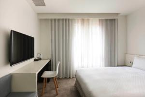 a hotel room with a bed and a desk with a television at CityInn Hotel Taipei Station Branch II in Taipei