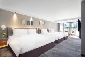 a hotel room with two beds and a tv at ILLUME Taipei in Taipei
