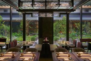 京都市にあるデュシタニ京都のテーブルと椅子、大きな窓のあるレストラン