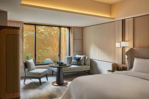 京都市にあるデュシタニ京都のベッド1台、椅子、窓が備わる客室です。