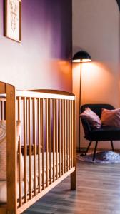 - un lit bébé dans une chambre avec une chaise et une lampe dans l'établissement Lilie location langevin, à Saint-Joseph