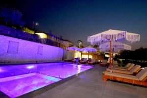 una piscina con sillas y sombrillas por la noche en Luxury Villa JO-AN, en Ksamil