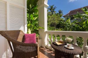 a porch with wicker chairs and a table with a book at The Luang Say Residence in Luang Prabang