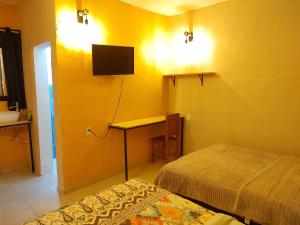 Cette chambre comprend deux lits et un bureau avec une télévision. dans l'établissement Casa Corazon, à Oaxaca