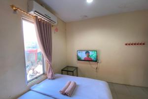 - une chambre avec un lit et une télévision murale dans l'établissement OYO 92932 Guesthouse Marbella, à Nongsa
