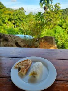 eine weiße Platte mit zwei Lebensmittelstücken auf dem Tisch in der Unterkunft Silver Hill Ecovillage in Kurunegala