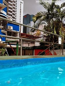 een blauw zwembad met gebouwen op de achtergrond bij Hostal Panama Experience in Panama-Stad