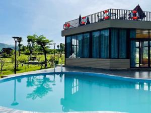 a villa with a swimming pool in front of a house at Caofong Glamping Village Hoà Bình in Hòa Bình