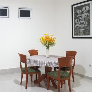 uma mesa de jantar com cadeiras e um vaso com flores em Rumah Benhil, Bendungan Hilir - Senayan em Jakarta