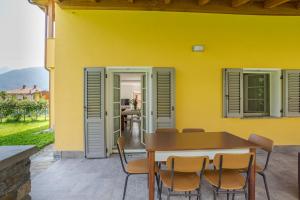una casa gialla con tavolo e sedie in legno di Casa Veligato 2 - Happy Rentals a San Siro