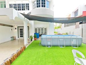 un patio al aire libre con piscina y césped en 527 BeachHouse l 5 bedroom with swimming pool - 3min walk to the beach en Tanjung Bungah