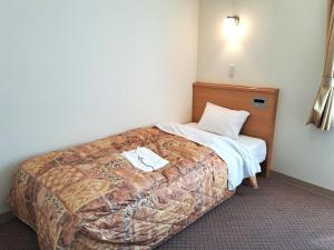a hotel room with a bed with a towel on it at Tetora Higashimuroran in Muroran