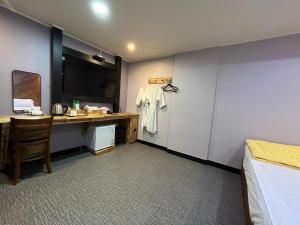 釜山にあるMaldives Hotel & Hostelのデスクとベッドが備わるホテルルームです。