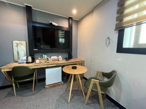 a room with a desk with a television and chairs at Maldives Hotel & Hostel in Busan