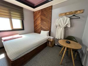 a small bedroom with a bed and a table at Maldives Hotel & Hostel in Busan