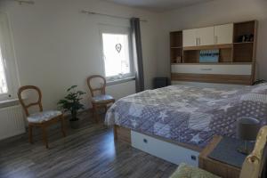 1 Schlafzimmer mit einem Bett und 2 Stühlen in der Unterkunft Dat Wittsche Hus - Ferienwohnung an der Nordsee in Wilhelmshaven