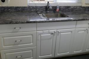 a kitchen counter with a sink and white cabinets at Cool, quiet ocean view 30 day min in Honolulu