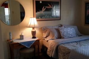 a bedroom with a bed and a table with a lamp at Cool, quiet ocean view 30 day min in Honolulu