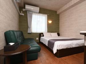 石垣島にあるホテルアビアンパナ石垣島のベッドと緑の椅子が備わるホテルルームです。