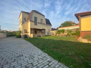 a house with a brick walkway next to a yard at Vila 1921 in Jevišovice