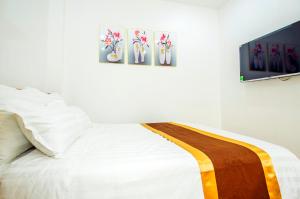 ein Schlafzimmer mit einem weißen Bett mit drei Gemälden an der Wand in der Unterkunft Sumitomo11 Apartment 5-39 Linh Lang in Hanoi