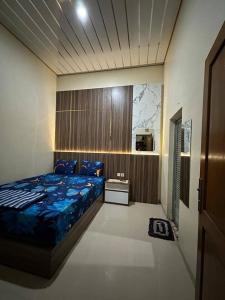 a bedroom with a bed with a blue comforter at David Guesthouse by XNR in Kemiri