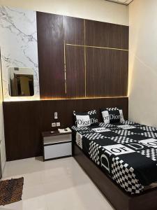 a bedroom with a black and white bed and a mirror at David Guesthouse by XNR in Kemiri