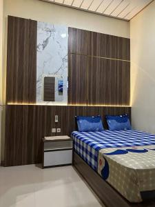 a bedroom with a bed with a blue and white blanket at David Guesthouse by XNR in Kemiri