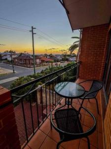una mesa y una silla en un balcón con vistas a la calle en Sunset views over South Fremantle en Fremantle