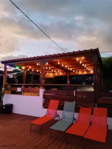 a deck with chairs and a pergola with lights at Les bungalows du chateau d'Ô in Petite Île