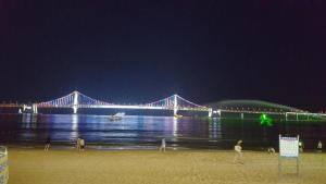 a bridge over the water at night with people on the beach at Maldives Hotel & Hostel in Busan