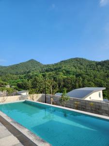 a swimming pool with a mountain in the background at Vesper Namhae in Namhae