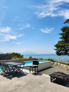a patio with a table and chairs and a pool at Vesper Namhae in Namhae