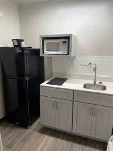 a kitchen with a sink and a black refrigerator at Artesia Inn- No Service Fees in Artesia