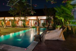 a swimming pool in front of a house at Asri Guesthouse in Canggu