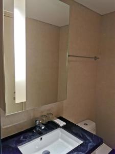 La salle de bains est pourvue d'un lavabo, d'un miroir et de toilettes. dans l'établissement Warhol Residence at Louis Kienne Semarang Simpang Lima, à Semarang