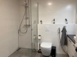 a white bathroom with a shower and a toilet at Kotimaailma Apartments Vapaudenkatu 47 in Jyväskylä