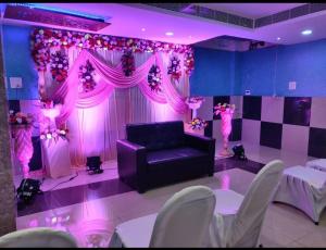a purple room with a couch and a stage with flowers at HOTEL AMAN in Allahābād