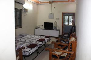 Habitación con 2 camas, sillas y TV. en Centaurus Homestay near Trichy Airport, en Tiruchchirāppalli