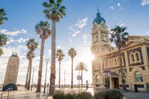 a building with a clock tower and palm trees at Durham Serviced Apartments in Adelaide