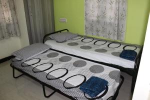 2 camas individuales en una habitación con paredes verdes en Centaurus Homestay near Trichy Airport, en Tiruchchirāppalli
