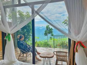 un homme et une femme assis sur une terrasse couverte donnant sur la fenêtre dans l'établissement Mai Hill Homestay, à Ải Hạ