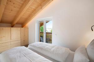 a white bedroom with a bed and a window at Ferienwohnung Wendelsteinblick in Bad Tölz