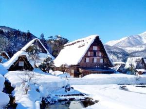 a house covered in snow with mountains in the background at Oyado Yunosato in Shirakawa