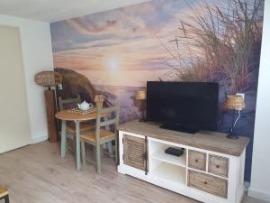 a living room with a tv and a dining room table at 't Hoekhuisje in Katwijk aan Zee