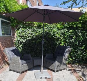 2 stoelen en een parasol op een patio bij 't Hoekhuisje in Katwijk aan Zee