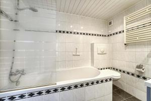La salle de bains blanche est pourvue d'une baignoire et de toilettes. dans l'établissement 't Hoekhuisje, à Katwijk aan Zee