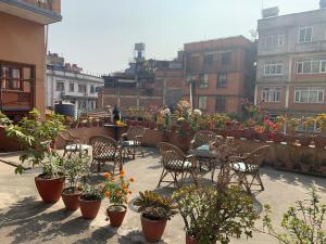 un patio con sillas, mesas y macetas en Lhasa Guest House en Katmandú